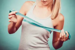 Woman measuring her breasts with measuring tape