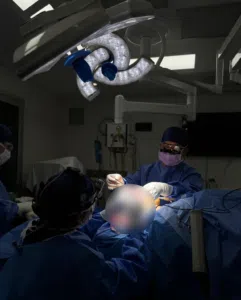 dr jack zoumaras performing surgery on a blurred out patient