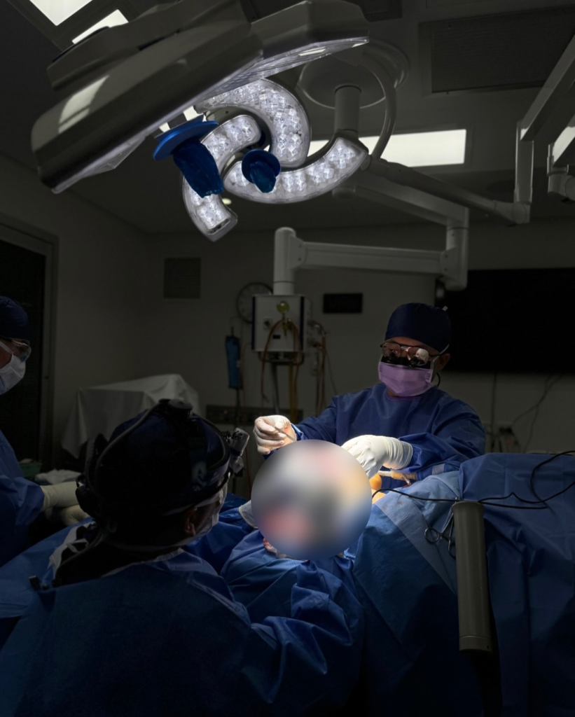 dr jack zoumaras performing surgery on a blurred out patient