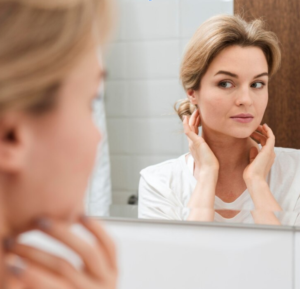 woman looking at skin in the mirror